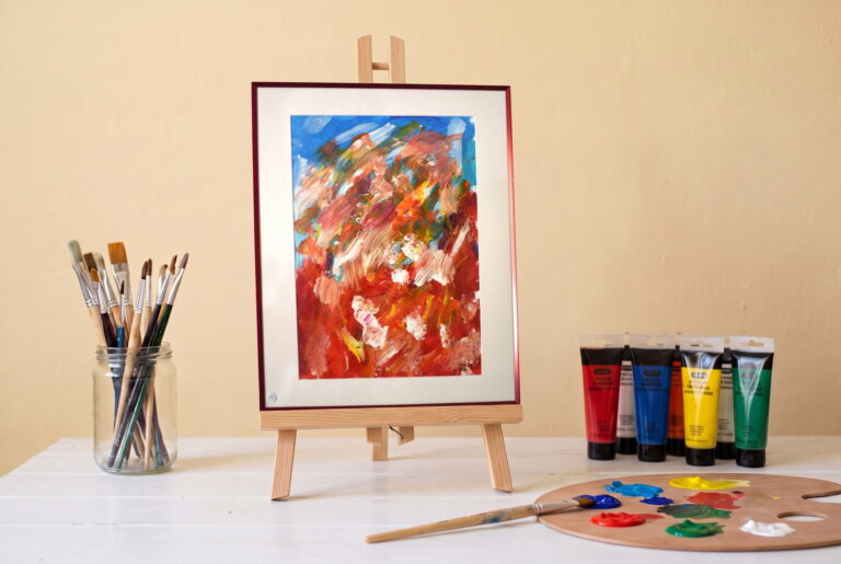 Pluie de confettis, peinture acrylique aux touches orange et blanches sur fond bleu, Mimie BB , posée sur un chevalet